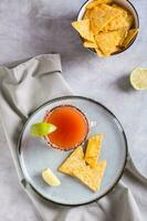 Michelagua mocktail with tomato juice and lime juice in a glass and nachos top and vertical view photo