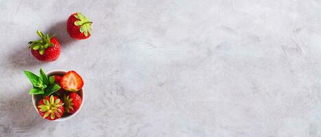 Fresh strawberries in a bowl and on a gray background top view web banner photo