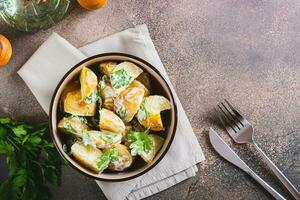 Potato salad in a peel with parsley and mayonnaise in a bowl on the table top view photo