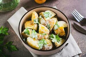 Delicious potato salad with parsley and mayonnaise in a plate on the table photo