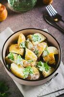 Delicious potato salad with parsley and mayonnaise in a plate on the table vertical view photo