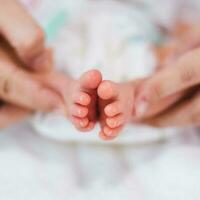 Newborn baby feet on white blanket. mother hold feets of newborn baby. Cmaternity and babyhood concept. photo