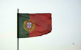 portugués bandera ondulación en el viento en contra un claro cielo foto