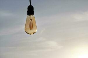 Single light bulb against a clear sky photo