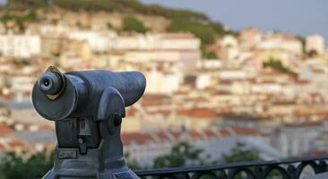 Viewpoint in Lisbon with selective focus on a telescope, with buildings and roof tops in the background photo