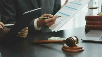 Business and lawyers discussing contract papers with brass scale on desk in office. Law, legal services, advice, justice and law concept picture with film grain effect video