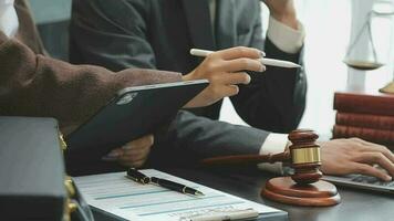 Business and lawyers discussing contract papers with brass scale on desk in office. Law, legal services, advice, justice and law concept picture with film grain effect video