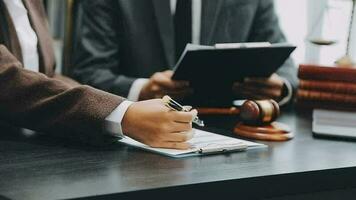 Business and lawyers discussing contract papers with brass scale on desk in office. Law, legal services, advice, justice and law concept picture with film grain effect video