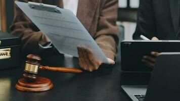 Business and lawyers discussing contract papers with brass scale on desk in office. Law, legal services, advice, justice and law concept picture with film grain effect video