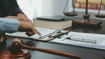 Business and lawyers discussing contract papers with brass scale on desk in office. Law, legal services, advice, justice and law concept picture with film grain effect video