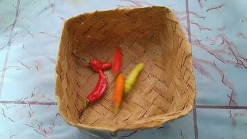 Video of fresh chilies falling in a wooden basket in the kitchen cooking room