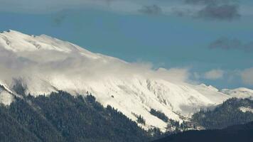 White clouds forming a swirling surface over Caucasus mountains. Scenic view of beautiful mountains, timelapse video