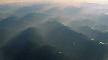 lindo Visão através avião janela, avião vôo acima nebuloso rio dentro montanhas. China território. video