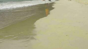 First person view walking along the beach in Phuket island on a sunny windy day. Sea waves cover people with their heads. Red warning flags Do not swim video