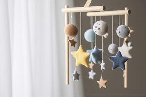 Baby crib mobile with stars, planets and moon. Kids handmade toys above the newborn crib. First baby eco-friendly toys made from felt and wood. Space for text, photo