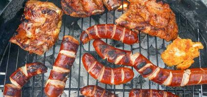 Grilled sausages and chicken on barbecue top view. Barbecue in the garden. Grilling meat. photo