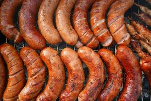 Grilled sausages on barbecue top view. Barbecue in the garden. Grilling meat. photo