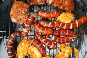 Grilled sausages and chicken on barbecue top view. Barbecue in the garden. Grilling meat. photo