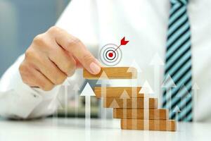 Hand holding a wooden block the top one with target icon symbol and arrow pointing up show growth business. Business strategy and target of business. photo