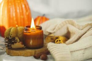 Autumn composition with aromatic candle in glass jar with wooden wick, and candle shape of pumpkins. Concept of aromatherapy, meditation and wellbeing photo