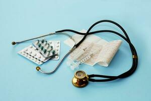 pills, phonendoscope, cardiogram, syringes on a blue background, modern medicine. photo