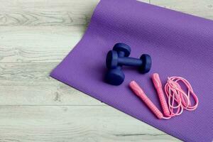 dumbbells with a jump rope on a gym mat photo