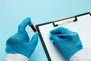 doctor holding a test tube with blood and making a note on paper photo