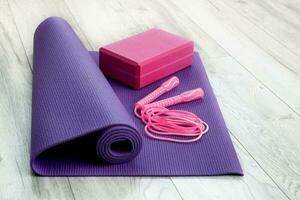 yoga brick and jump rope on purple gym mat photo