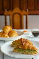 Croissant sandwich with egg,avocado on white dish and honey, coffee. breakfast and healthy food concept. photo