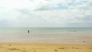 Beach with tourists, an airplane is flying overhead. Airplane is landing. Jet coming in to land video