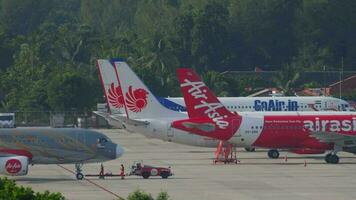 phuket, Tailandia noviembre 29, 2019 - tractor remolque aerobús a320 de airasia universidad tecnología Malasia librea a el terminal a phuket aeropuerto. aeropuerto delantal y aeronave estacionamiento video