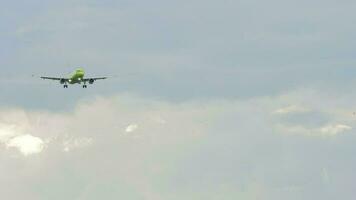 irreconocible aeronave con verde librea en el cielo. avión que se acerca para aterrizaje, frente vista. lento movimiento, avión de línea es volador video