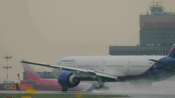 MOSCOW, RUSSIAN FEDERATION JULY 28, 2021 - Boeing 777 of Aeroflot takeoff at Sheremetyevo Airport. Spray from under the landing gear on a wet runway. Tourism and travel concept video