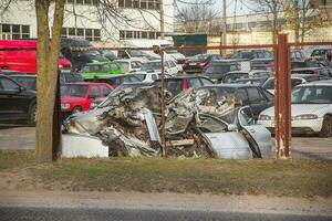 Broken gray car in the parking lot. Car parking behind a fence. With copy space for text or design. photo