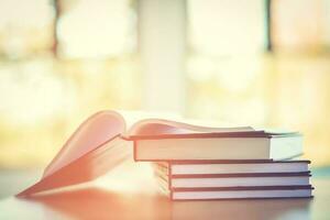 Pile of old books on the table with sunlight and copy space, Stack and one open book, Education learning concept. photo