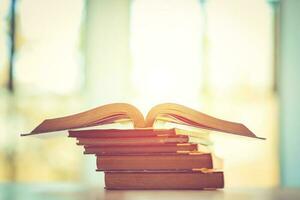 Pile of old books on the table with sunlight and copy space, Stack and one open book, Education learning concept. photo