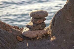 interesting tower made of stones arranged on the shore of the ocean on a warm summer's day photo