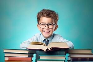 portrait of a happy child little boy with glasses sitting on a stack of books and reading a books, light blue background. photo