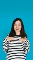 Portrait of a gorgeous, pretty, imposing girl in a striped pullover with her arms across her chest, isolated on a blue background photo