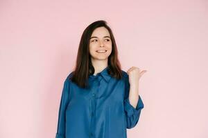 Radiant Portrait of Beautiful Woman with Joyful Smile, Pointing Finger and Looking at Empty Space, Isolated on Pink Background - News and Excitement Concept photo