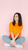 Dreaming in Serenity. Beautiful Woman Seated Comfortably in Lotus Position, Gazing into Empty Space, Yearning for a New Love - Tranquil Mood on Pink Background photo