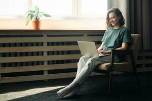 Efficiency and Flexibility, Young Woman Embraces Remote Work and Study, Utilizing Laptop at Home. Versatile Lifestyle of Freelancing, Business, and Self-Determination in a Cozy Home Environment. photo