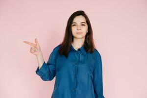 Positive Woman Pointing with Finger, Sharing Useful Tips in Empty Space. Conceptual Photo on Pink Background