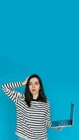 Emotional Young Woman in Striped Sweater Distraught by Bad News on Laptop - Expressive Female Feeling Sad and Disheartened - Isolated Blue Background - Perfect for Conceptual, Emotional photo