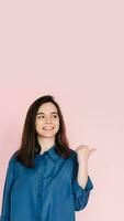 Radiant Portrait of Beautiful Woman with Joyful Smile, Pointing Finger and Looking at Empty Space, Isolated on Pink Background - News and Excitement Concept photo