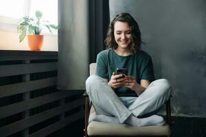 digital estilo de vida, joven mujer se involucra en comunicación y productividad mediante teléfono inteligente en el comodidad de hogar. un mezcla de estudiar, trabajar, y conexión en el digital años foto