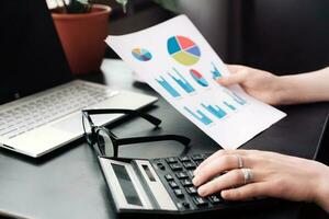 Focused Businesswoman. Analyzing Financial Budget and Calculating Finance Report in Office, Proficiently Engaged in Finance, Accounting, and Financial Analysis using Calculator and Document photo