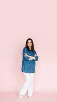 Confident businesswoman in stylish smart casual outfit, standing with folded hands, isolated on pink background, full body shot photo