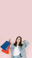 Joyful Shopper. Young Woman in Denim Shirt Celebrating, Arm Raised in Excitement, Against Pink Background, Delighted by Online Shopping or Amazing Find photo