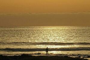 picturesque ocean landscape with the setting sun in a tropical country during summer holidays with fisherman photo